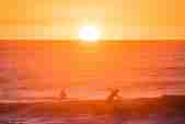 Two surfers in the sunset at Watergate Bay