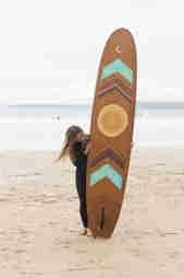 Maia Walczak artist standing next to longboard on the beach