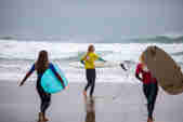 Three English National competitors walk their boards down to the sea