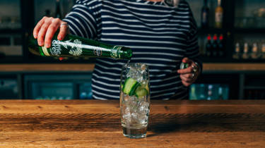 Glass of elderflower and mint cooler cocktail being poured