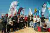 Competitors stand on the beach holding trophies from the English National Surfing Champtionship event in 2021 on Watergate BAy beach