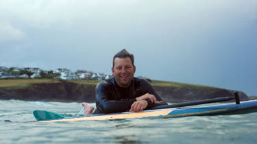 Andy Cameron leaning on his surfboard 