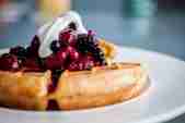 Waffles topped with mixed fruits and yoghurt