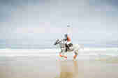Polo jockey riding a horse on the beach