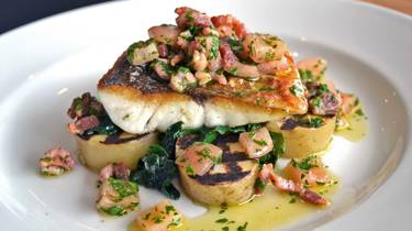 A plate of wild sea bass, potatoes, spinach and tomato