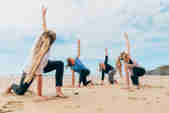 A group of four practice yoga on the beach