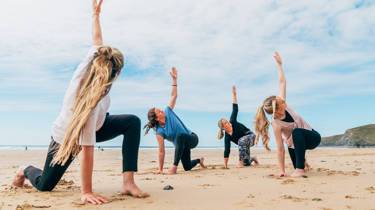 A group of four practice yoga on the beach