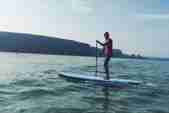 A stand up paddleboarder on the water off Watergate Bay beach
