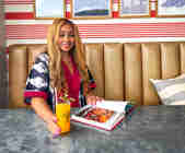 Lerato Umah-Shaylor sitting at a table in the Living Space with her cook book