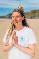 A yoga instructor holds her hands together in a prayer on the beach at Watergate Bay