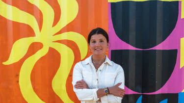 Clara Jonas stands in front of her colourful mural on the side of the beach food building at Watergate Bay