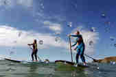Three people standup paddleboarding on the water at Watergate Bay