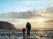 Father and son enjoying a walk at dusk on the beach