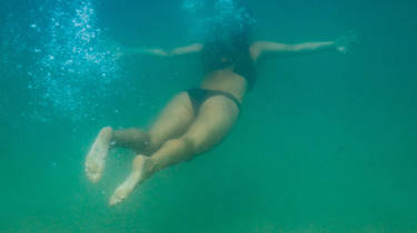A lady dives under the clear blue water