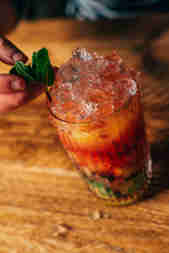 Orange and passionfruit mocktail in a glass with crushed ice and a mint sprig