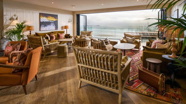 A snug area with chairs and tables facing a sea view