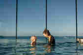  Mother and toddler enjoying the infinity pool with the sea view behind them