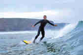 A man rides a wave on a surfboard at Watergate Bay