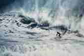A surfer rides a wave in a storm