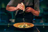 Chef grates parmesan cheese onto a plate in Zacry's restaurant